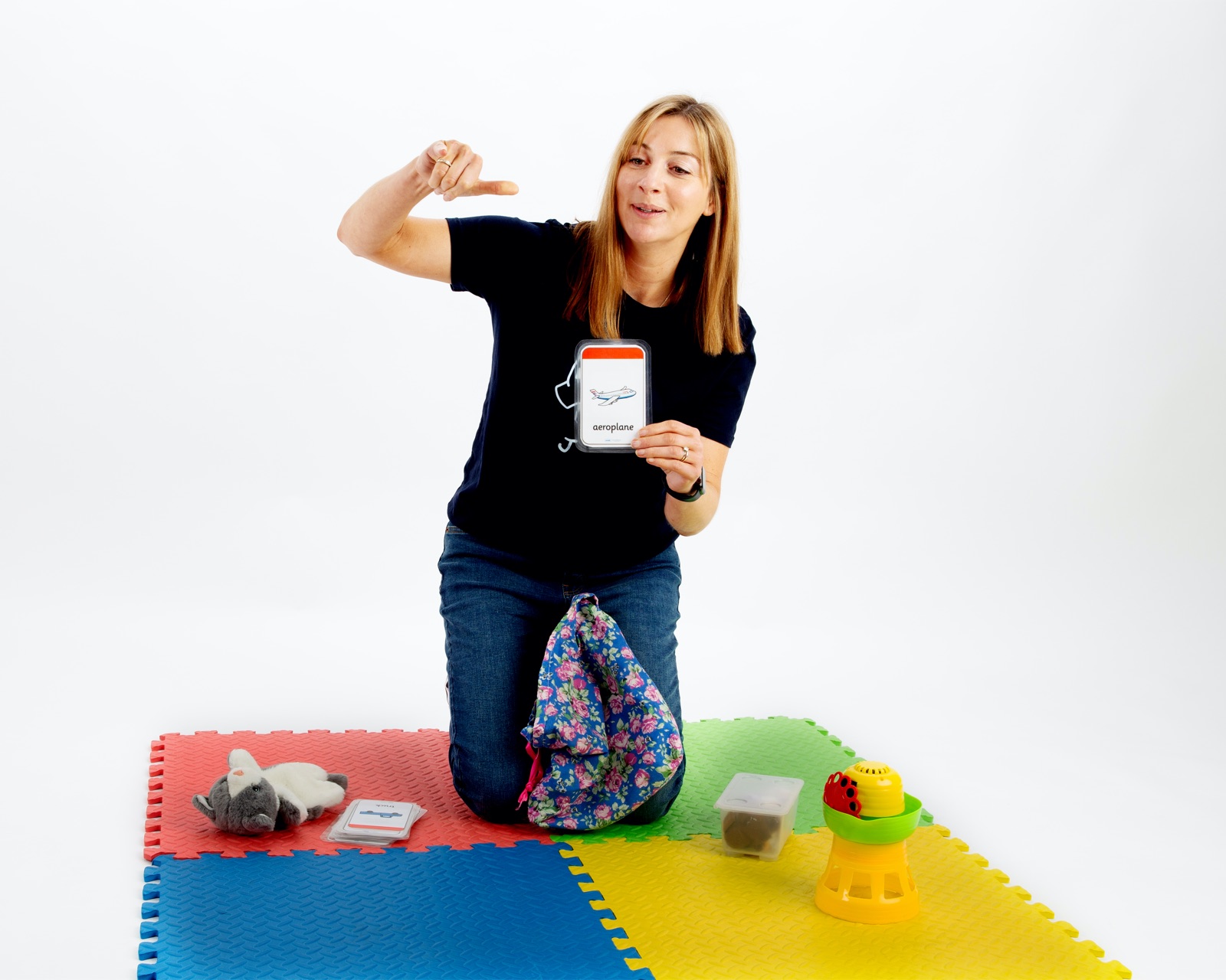 Jen signing with a symbol card on a colourful play mat